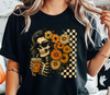 Person wearing a black t-shirt with a Boho floral skeleton DTF transfer with sunglasses and checkered background.