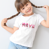 Child wearing a white t-shirt with colorful graphics and text, standing against a plain background.