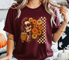 A close-up of a model wearing a red t-shirt featuring Boho Floral Skeleton DTF transfer! This vibrant design features a cool skeleton in sunglasses with a groovy floral hairstyle and a retro checkered background.