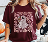 Person wearing a maroon t-shirt with a lace ghost DTF transfer design and floral patterns applied to the t-shirt.