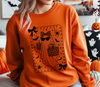 Spooky-cute boho leopard ghost design on an orange Halloween sweatshirt worn by a model.
