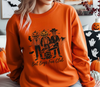 Person wearing an orange sweatshirt with Halloween-themed design in a casual setting.
