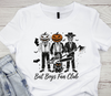 White t-shirt with Halloween-themed design featuring skeletons, pumpkins, and text 'Bat Boys Fan Club' on a wooden surface.