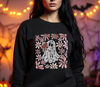 Close-up on a black t-shirt worn by a model, featuring a DTF transfer of a delicate lace ghost holding daisies, framed by retro floral graphics – a spooky-cute style.