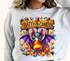 A sweatshirt with a graphic design featuring a cartoon bat holding a candy, surrounded by candy canes and the text 'BATTY FOR CANDY'.